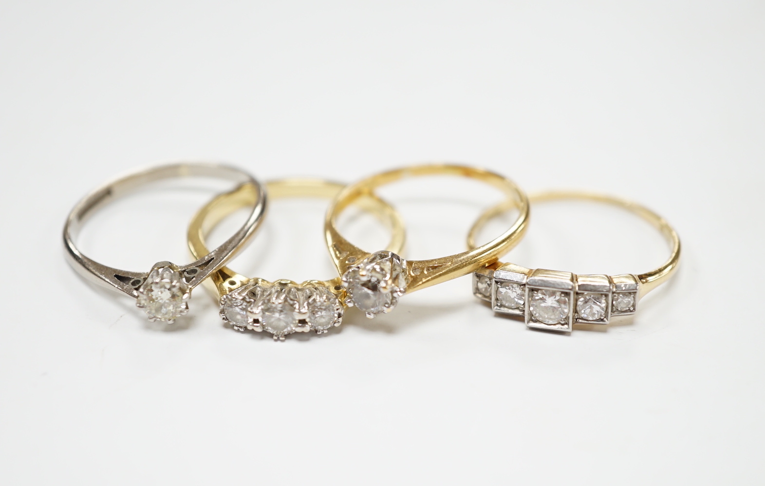 Four assorted 18ct and diamond set rings including a graduated five stone, three stone and two solitaires, gross weight 10.3 grams.